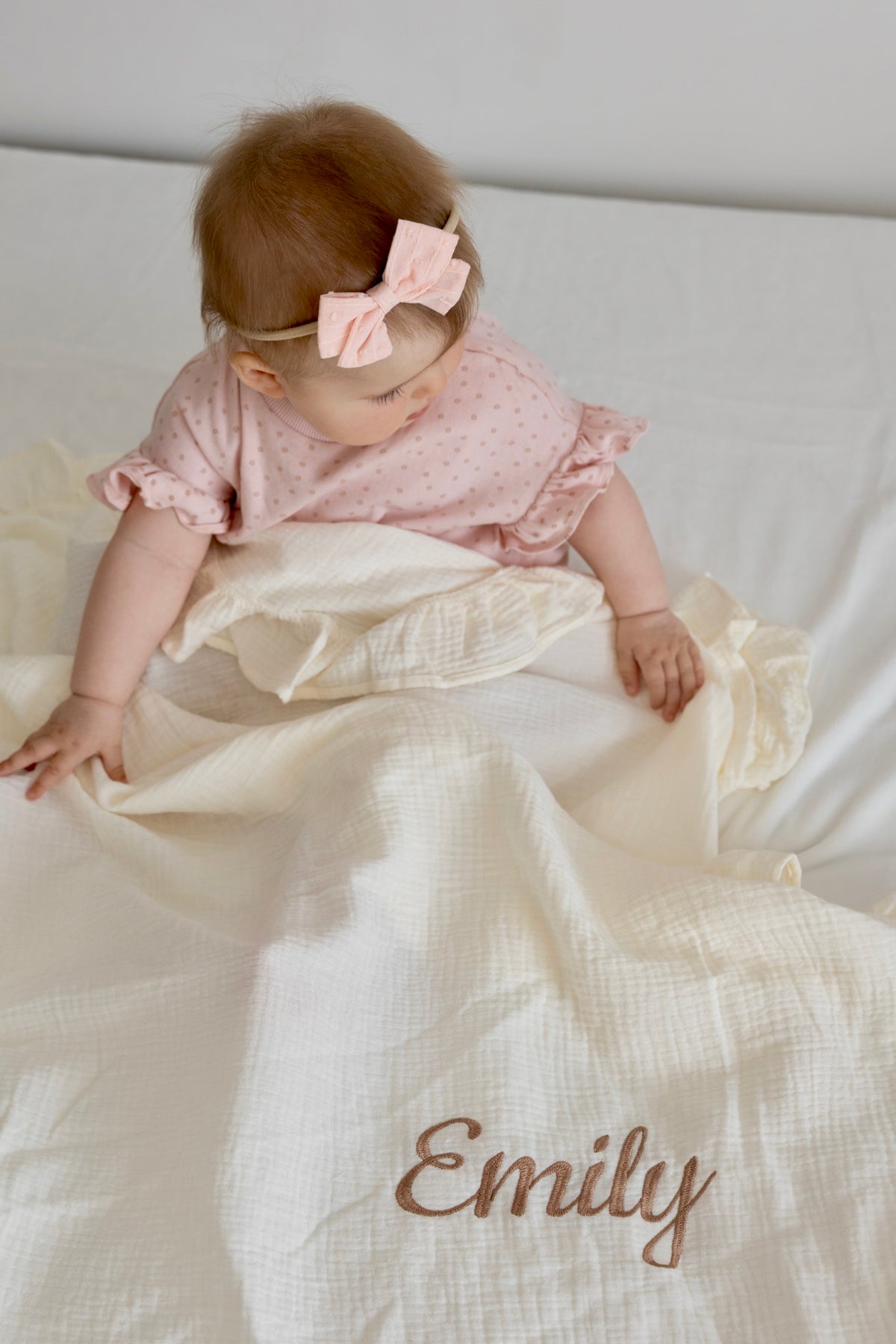 Personalised muslin baby blanket with embroidered name, shown with a baby