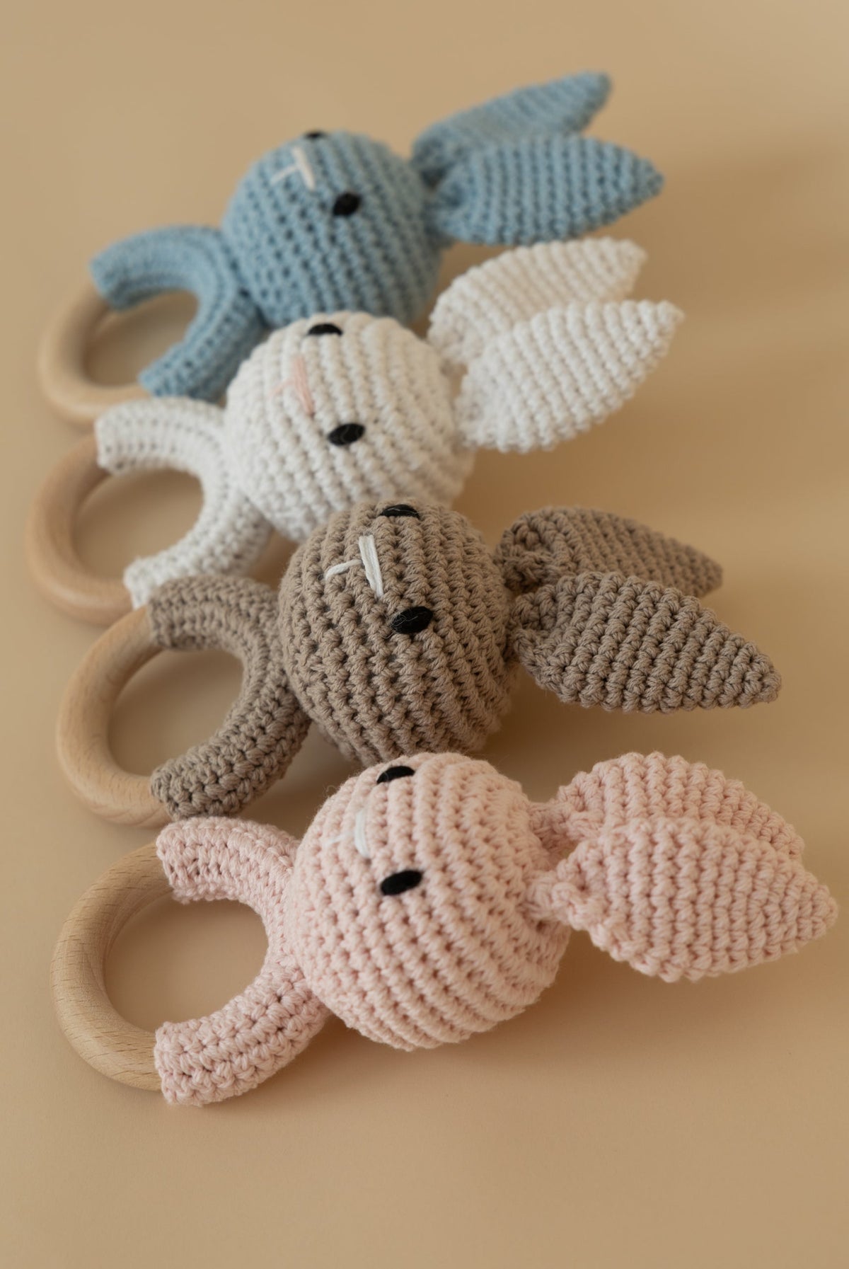 Crochet bunny teether toys with natural wooden rings in pastel blue, white, beige and pink