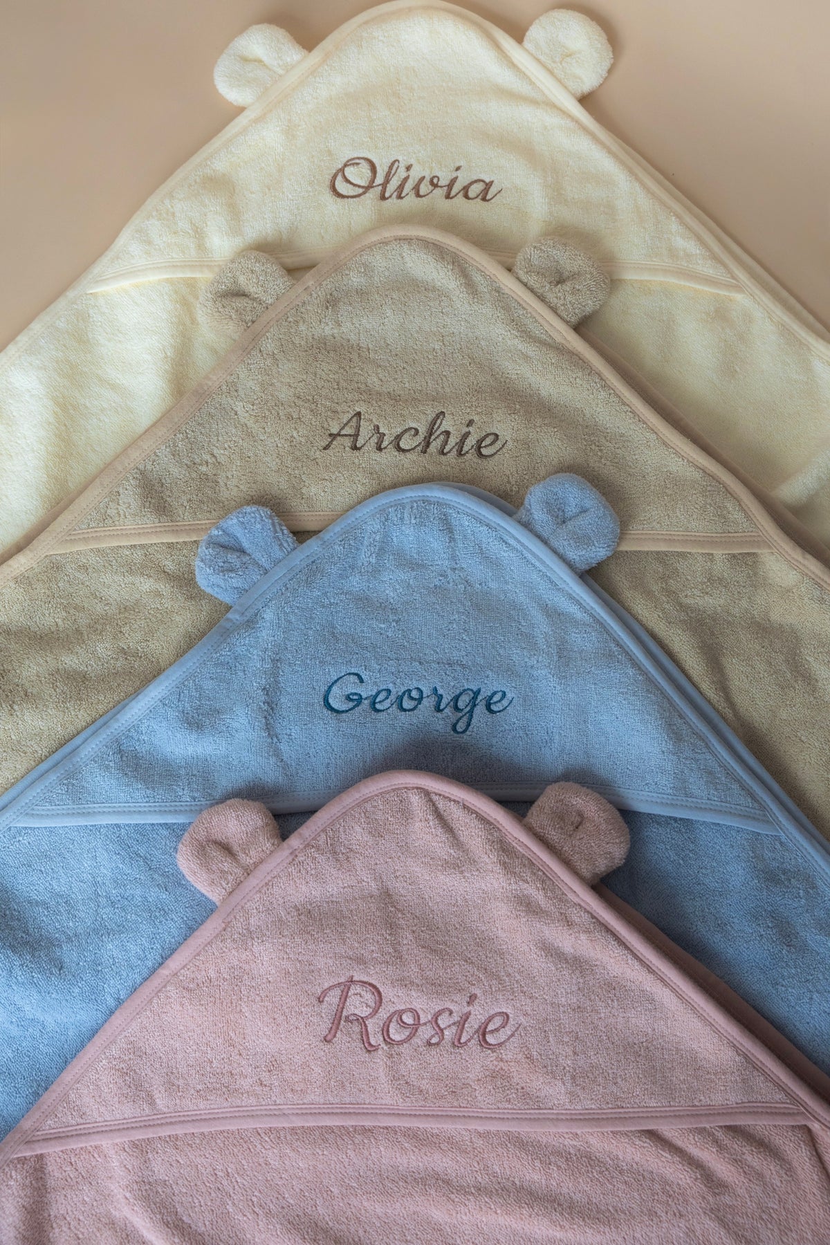 Personalised baby hooded towels in cream, beige, blue and pink with embroidered names